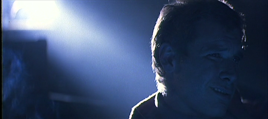 Deckard smirks in a smoke-filled projection room